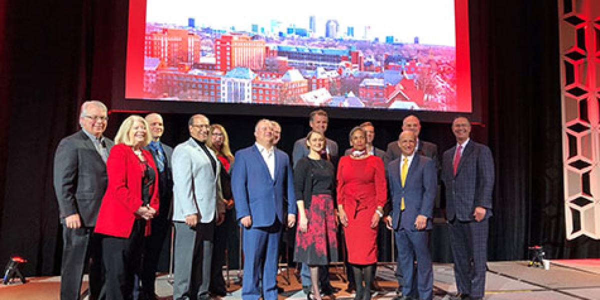 photo of the speakers posing underneath the event banner