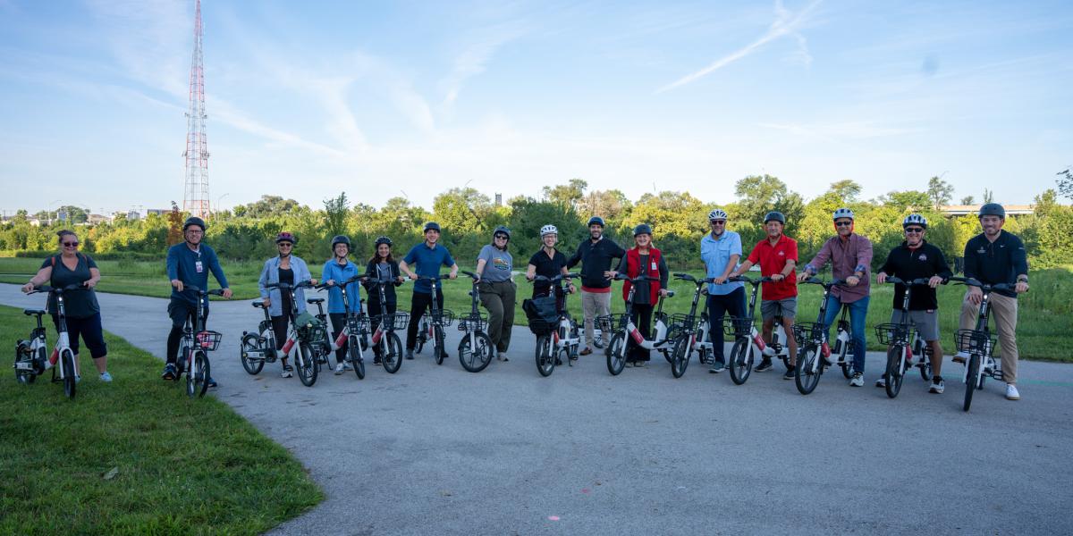 A group of people sitting on electric bicycles lined up, smiling.
