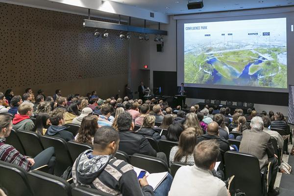 auditorium full of event attendees looking at river imagery
