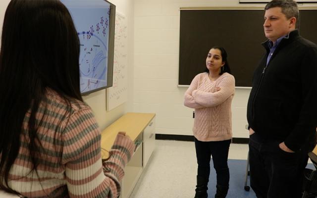 three people having conversation in a classroom