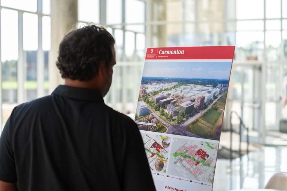 A man looking at a poster board that reads "Carmenton"