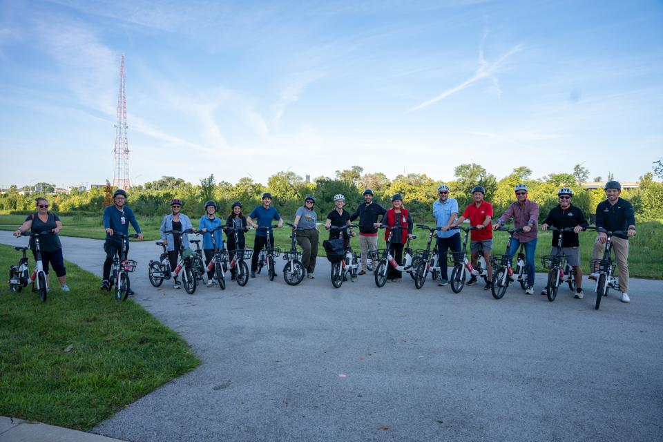 A group of people sitting on electric bicycles lined up, smiling.